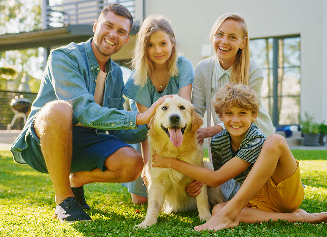 Personal Insurance - Closeup Portrait of a Smiling Family with a Son and Daughter Spending Time Together in the Backyard on the Green Grass with Their Dog
